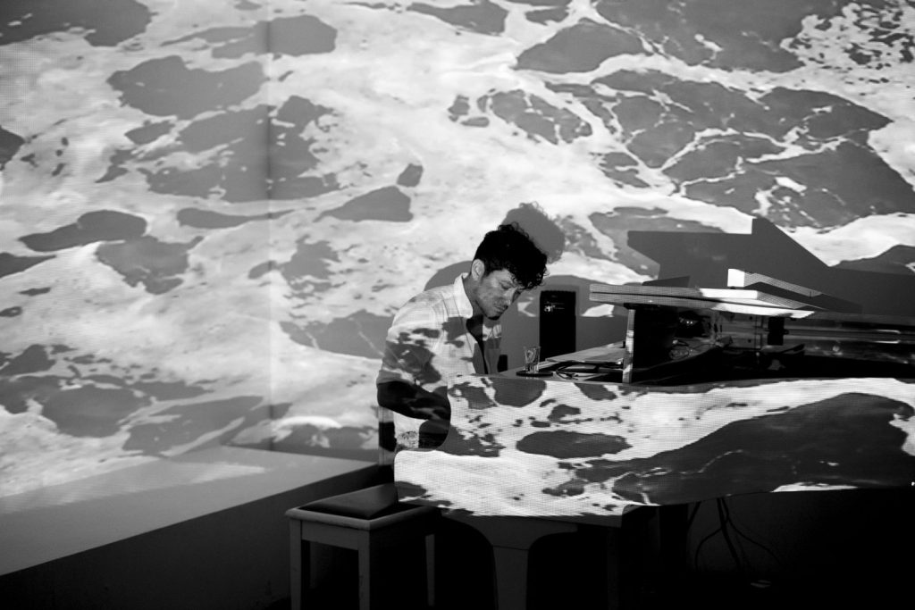 Oli Chang playing piano under ocean projections at his Spaces Between EP launch in Room 13 at The Slow