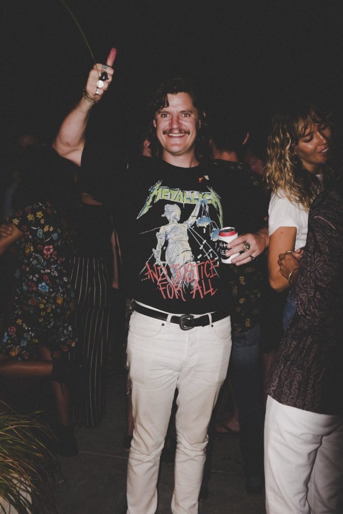 Guest in a Metallica T-shirt raising a hand at the On the Roof: Noise in My Head party at The Slow