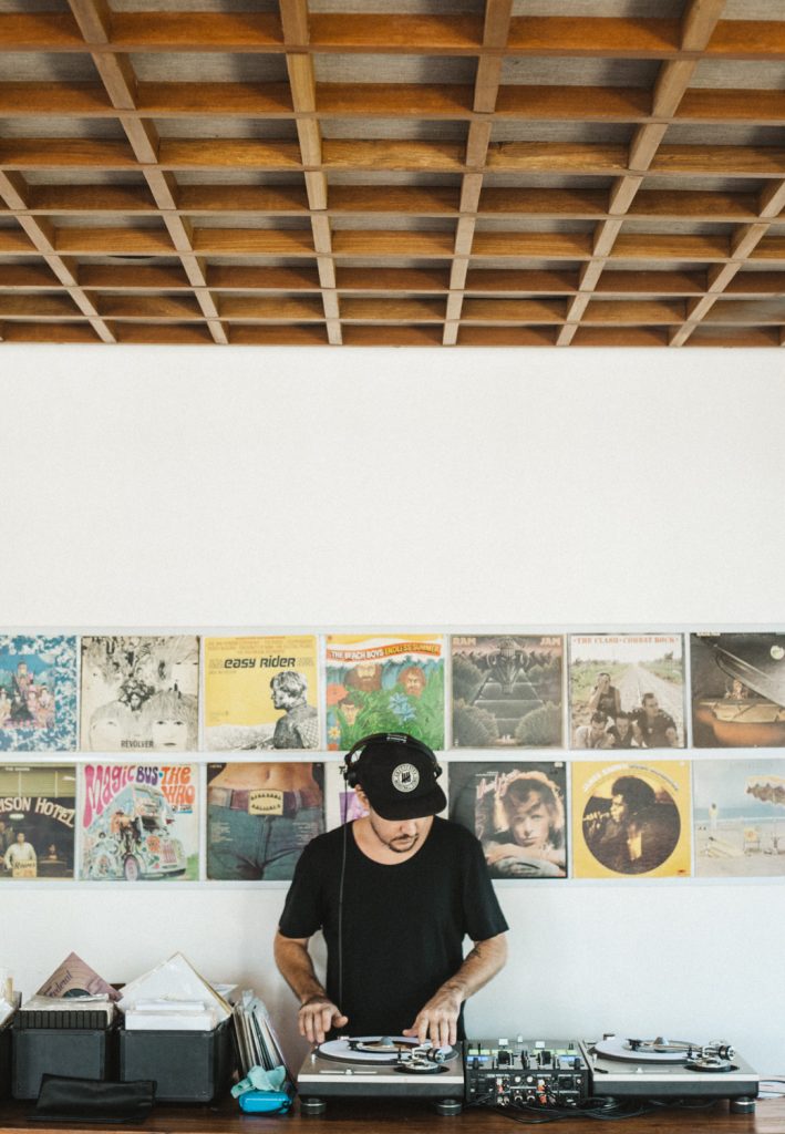 DJ at the turntables beneath a wall of vinyl album covers during Sunday Brunch: Sound Bites at The Slow
